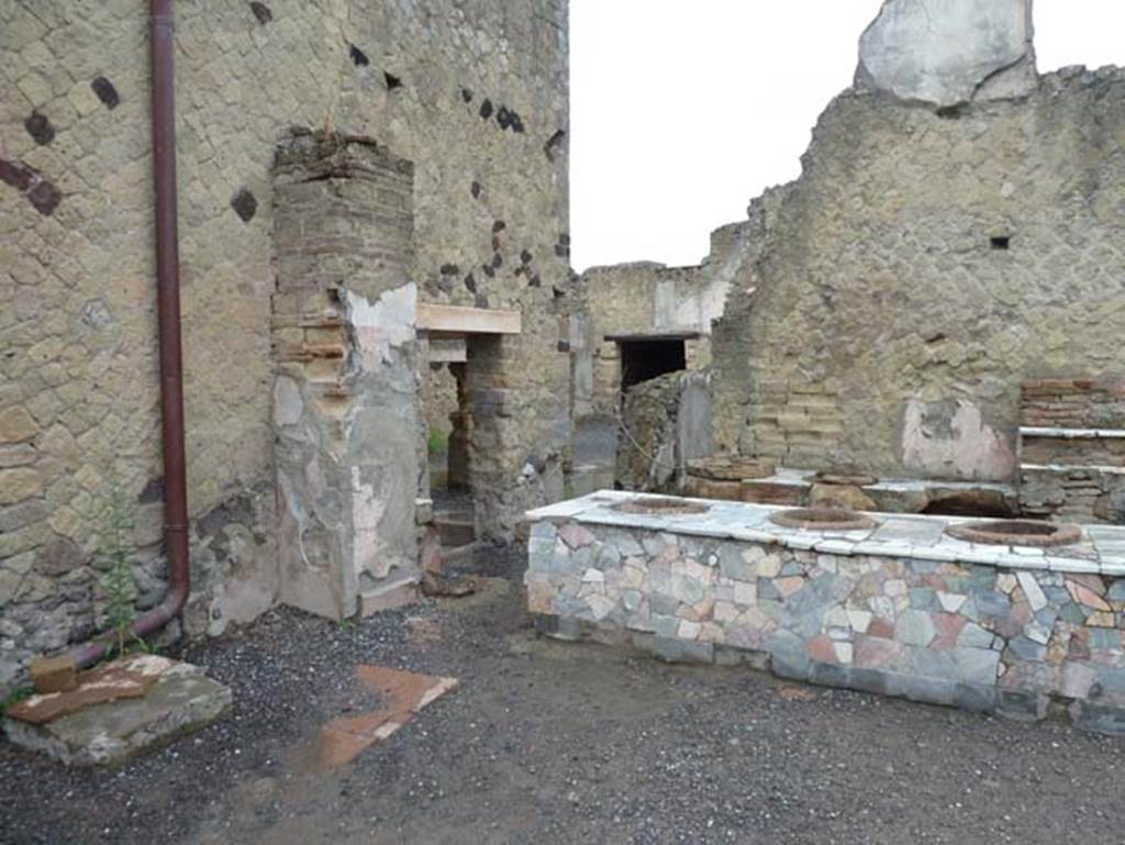 IV.16, Herculaneum, September 2015. Looking south-west across counter.
On the left, in the south-east corner, is a floor of tiles which has been interpreted as the presence of a trace of a latrine. According to Maiuri, there was a cooking stone in the south-east corner.